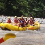 Seven people in a rubber boat going down the rapids